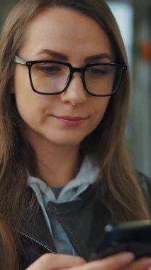 Public transport. Woman in glasses in tram using smartphone chatting and texting with friends, slow motion. City, urban, transportation.