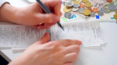 Aylık ev giderleri, vergiler, banka hesap bakiyesi ve kredi kartı faturaları hesaplayan bir kadın. Giderler için gelir yeterli değil.