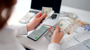 Aylık ev giderleri, vergiler, banka hesap bakiyesi ve kredi kartı faturaları hesaplayan bir kadın. Giderler için gelir yeterli değil.
