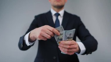 Resmi olarak giyinmiş bir adam Amerikan Doları 'nı kameraya doğru savuruyor. Yatırım, başarı, finansal beklentiler veya kariyer gelişimi kavramı. Yavaş çekim