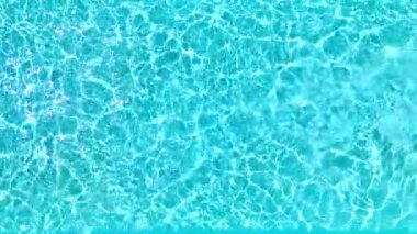 Yüzme havuzundaki saf mavi suyun yüzeyinde ışık yansımaları var. Hava görüntüleri, yukarıdan aşağıya doğru. Yavaş çekim