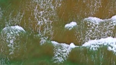 Deniz dalgaları kumlu sahil şeridinde dalgalanırken hiç bitmeyen güzel ve kusursuz görüntülerin drone görüntüsü. Turkuaz dalgalarla karşılaşan altın kumları olan el değmemiş bir plajın çarpıcı hava manzarası.