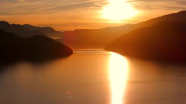 Vancouver 'ın kuzeyindeki güzel günbatımında deniz manzarası. Dağların siluetlerinin üzerine güneş batıyor. British Columbia, Kanada.