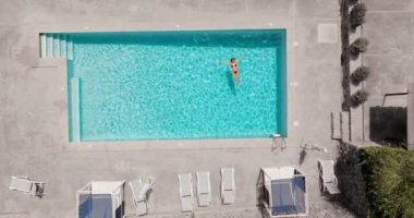 Pembe mayo giymiş bir kadının havuzda sırt üstü yatışı. Rahatlatıcı konsept, yaz yaşam tarzı. 