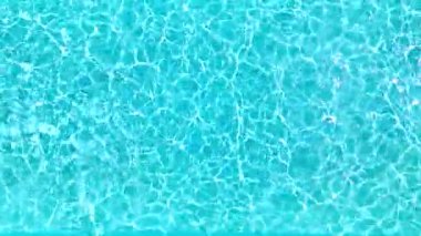 Yüzme havuzundaki saf mavi suyun yüzeyinde ışık yansımaları var. Hava görüntüleri, yukarıdan aşağıya doğru. Yavaş çekim