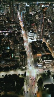 Geceleri Vancouver 'ın merkezindeki göz kamaştırıcı hava manzarası. British Columbia, Kanada. Dikey video