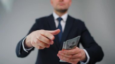 Resmi olarak giyinmiş bir adam Amerikan Doları 'nı kameraya doğru savuruyor. Yatırım, başarı, finansal beklentiler veya kariyer gelişimi kavramı. Yavaş çekim