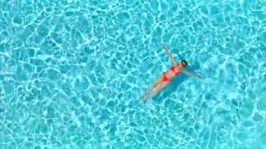 Pembe mayo giymiş bir kadının havuzda sırt üstü yatışı. Rahatlatıcı konsept, yaz yaşam tarzı. Havuz ve çöl manzarası. Yavaş çekim