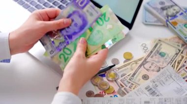 Aylık ev giderleri, vergiler, banka hesap bakiyesi ve kredi kartı faturaları hesaplayan bir kadın. Giderler için gelir yeterli değil.