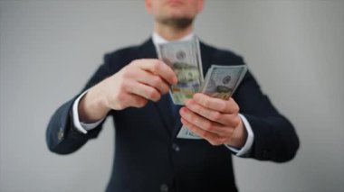 Resmi olarak giyinmiş bir adam Amerikan Doları 'nı kameraya doğru savuruyor. Yatırım, başarı, finansal beklentiler veya kariyer gelişimi kavramı. Yavaş çekim