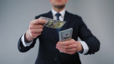 Resmi olarak giyinmiş bir adam Amerikan Doları 'nı kameraya doğru savuruyor. Yatırım, başarı, finansal beklentiler veya kariyer gelişimi kavramı. Yavaş çekim