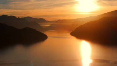 Vancouver 'ın kuzeyindeki güzel günbatımında deniz manzarası. Dağların siluetlerinin üzerine güneş batıyor. British Columbia, Kanada.