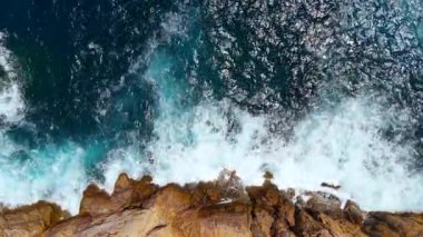 Hava manzaralı deniz kıyısı uçurumları kayalara çarpıyor. Kayalık sahil suyla buluşuyor. Güney Sardunya, İtalya. İnsansız hava aracı görüntüleri
