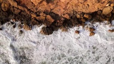 Hava manzaralı deniz kıyısı uçurumları kayalara çarpıyor. Kayalık sahil suyla buluşuyor. Güney Sardunya, İtalya. İnsansız hava aracı görüntüleri