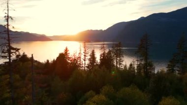 Vancouver 'ın kuzeyindeki güzel günbatımında deniz manzarası. Dağların siluetlerinin üzerine güneş batıyor. British Columbia, Kanada.