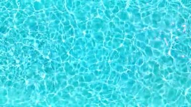 Yüzme havuzundaki saf mavi suyun yüzeyinde ışık yansımaları var. Hava görüntüleri, yukarıdan aşağıya doğru. Yavaş çekim