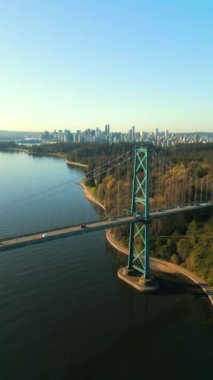 Şafakta Lions Gate Köprüsü ve Stanley Parkı 'nın havadan görüntüsü. Arka planda Vancouver şehir merkezi var. Britanya Kolombiyası Kanada. Dikey video.