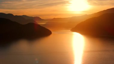 Vancouver 'ın kuzeyindeki güzel günbatımında deniz manzarası. Dağların siluetlerinin üzerine güneş batıyor. British Columbia, Kanada.
