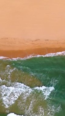 Güzel bir sahil ve deniz manzarası. Dalgalar kumlu sahilde yuvarlanıyor. Kumda dalgalar, rahatlatıcı bir tatil fotoğrafı. Deniz ve karanın buluşma yeri. Sardunya, İtalya