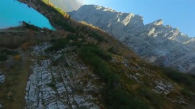 Keskin dağ uçurumlarına yakın uçan FPV insansız hava aracı ve Lago di Sorapis: Dolomitler, İtalya 'daki Turkuaz Dağı Gölü.