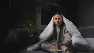 Hasta kız grip olmuş ya da nezle olmuş, alerji belirtileri gösteriyor. Alerjisi olan genç bir kadın mendil içinde hapşırıyor, burnunu siliyor ve çay içiyor. Sağlıksız kadın mevsimsel virüs hastalığından muzdarip..