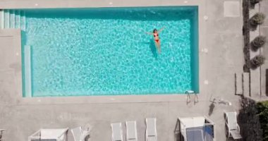 Kırmızı mayo giymiş bir kadının havuzda sırt üstü yatışı. Rahatlatıcı konsept, yaz yaşam tarzı. 