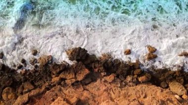 Hava manzaralı deniz kıyısı uçurumları kayalara çarpıyor. Kayalık sahil suyla buluşuyor. Güney Sardunya, İtalya. İnsansız hava aracı görüntüleri