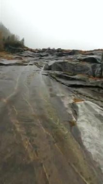 Mistik sonbahar manzarası. FPV dronu, suyun aktığı taş yüzeyin yakınındaki siste hızla uçar. Malta, Avusturya. Dikey video