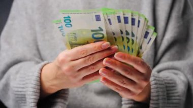Avro banknotlarını sayan bir kadın, yakın plan. Yatırım, başarı, finansal beklentiler veya kariyer ilerlemesi kavramı.