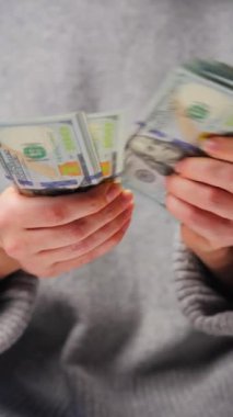 Amerikan Doları 'nı sayan bir kadın, yakın plan. Yatırım, başarı, finansal beklentiler veya kariyer gelişimi kavramı. Dikey video
