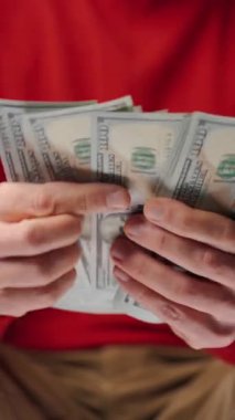 ABD Doları banknotlarını sayan adam, yakın plan. Yatırım, başarı, finansal beklentiler veya kariyer gelişimi kavramı. Dikey video