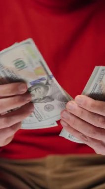 ABD Doları banknotlarını sayan adam, yakın plan. Yatırım, başarı, finansal beklentiler veya kariyer gelişimi kavramı. Dikey video