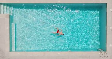 Kırmızı şortlu bir adam havuzda sırtüstü yüzüyor. Rahatlatıcı konsept, yaz yaşam tarzı. Yavaş çekim