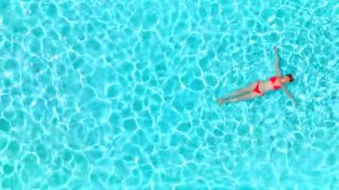 Pembe mayo giymiş bir kadının havuzda sırt üstü yatışı. Rahatlatıcı konsept, yaz yaşam tarzı. 