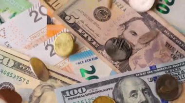 Bozuk paralar farklı para birimlerinin ve banknotların üzerine düşer. Makro çekim, yavaş çekim.