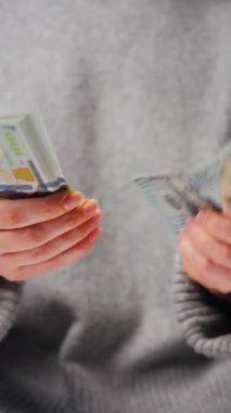 Amerikan Doları 'nı sayan bir kadın, yakın plan. Yatırım, başarı, finansal beklentiler veya kariyer gelişimi kavramı. Dikey video