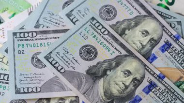 Karmaşık tasarımı ve çeşitli güvenlik özelliklerini vurgulayan 100 dolarlık banknotların yakından ve ayrıntılı görüntüsü. Yavaş çekim
