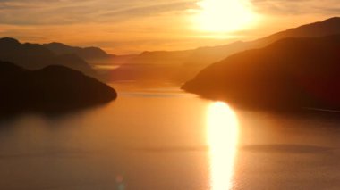 Vancouver 'ın kuzeyindeki güzel günbatımında deniz manzarası. Dağların siluetlerinin üzerine güneş batıyor. British Columbia, Kanada.