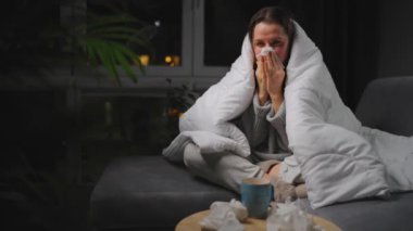 Hasta kız grip olmuş ya da nezle olmuş, alerji belirtileri gösteriyor. Alerjisi olan genç bir kadın mendil içinde hapşırıyor, burnunu siliyor ve çay içiyor. Sağlıksız kadın mevsimsel virüs hastalığından muzdarip..