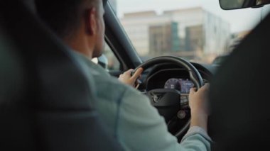 Gün batımında şehrin sokaklarında araba süren adamın arka koltuğu..