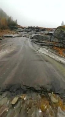 Mistik sonbahar manzarası. FPV dronu, suyun aktığı taş yüzeyin yakınındaki siste hızla uçar. Malta, Avusturya. Dikey video