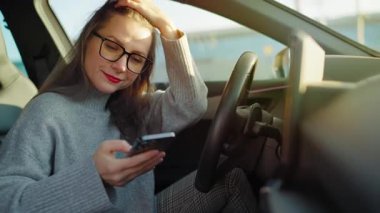 Arabada beklerken akıllı telefon kullanan mutlu bir kadının portresi..
