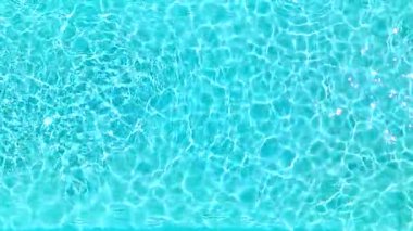 Yüzme havuzundaki saf mavi suyun yüzeyinde ışık yansımaları var. Hava görüntüleri, yukarıdan aşağıya doğru. Yavaş çekim