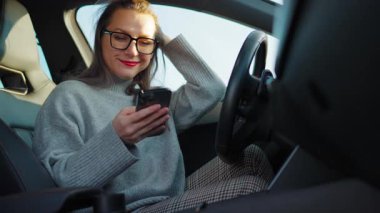 Arabada beklerken akıllı telefon kullanan mutlu güzel bir kadının portresi. Yavaş çekim