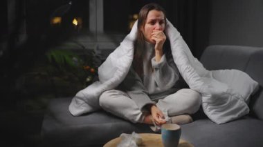 Hasta kız grip olmuş ya da nezle olmuş, alerji belirtileri gösteriyor. Alerjisi olan genç bir kadın mendil içinde hapşırıyor, burnunu siliyor ve çay içiyor. Sağlıksız kadın mevsimsel virüs hastalığından muzdarip..