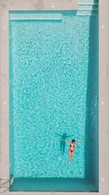 Kırmızı mayo giymiş bir kadının havuzda sırt üstü yatışı. Rahatlatıcı konsept, yaz yaşam tarzı. Dikey video