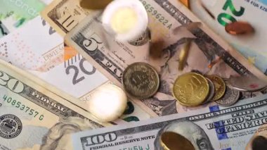 Bozuk paralar farklı para birimlerinin ve banknotların üzerine düşer. Makro çekim, yavaş çekim.