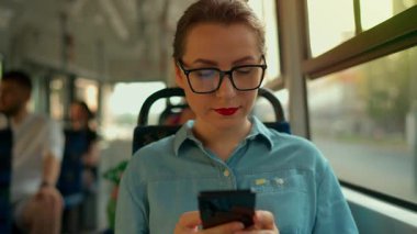 Toplu taşıma. Tramvaydaki gözlüklü kadın akıllı telefon konuşmaları yapıyor ve arkadaşlarıyla mesajlaşıyor. Şehir, şehir, ulaşım. Yavaş çekim