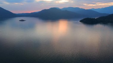 Akşamları Vancouver 'ın kuzeyindeki deniz manzarası. Mavi bulutlu gökyüzü ve dağların siluetleri. British Columbia, Kanada.