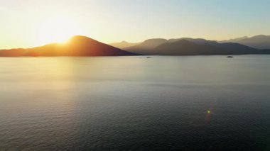 Vancouver 'ın kuzeyindeki güzel günbatımında deniz manzarası. Dağların siluetlerinin üzerine güneş batıyor. British Columbia, Kanada.